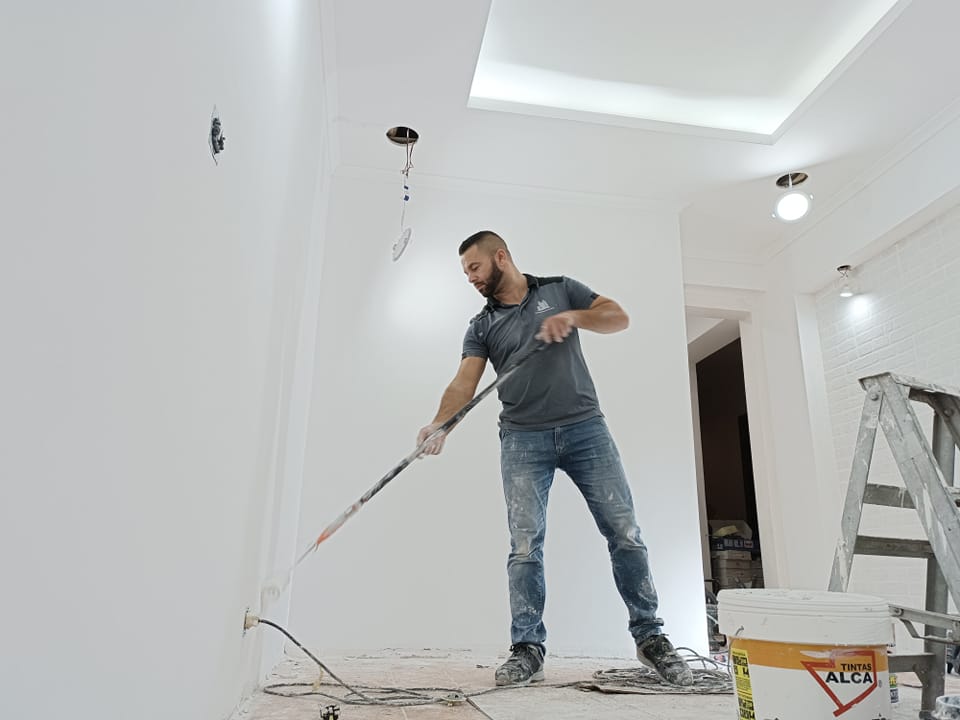 Pintor a aplicar tinta no teto de uma divisão