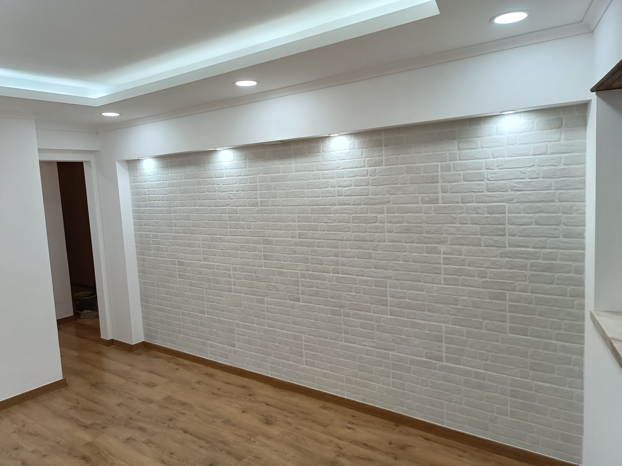 Sala com teto em pladur, sanca com iluminação LED e parede de revestimento