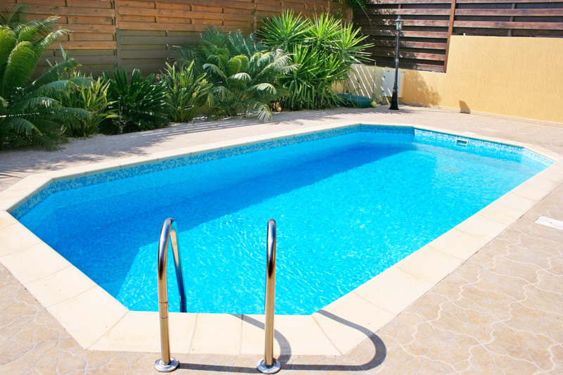 Piscina exterior limpa com água cristalina e zona envolvente ajardinada