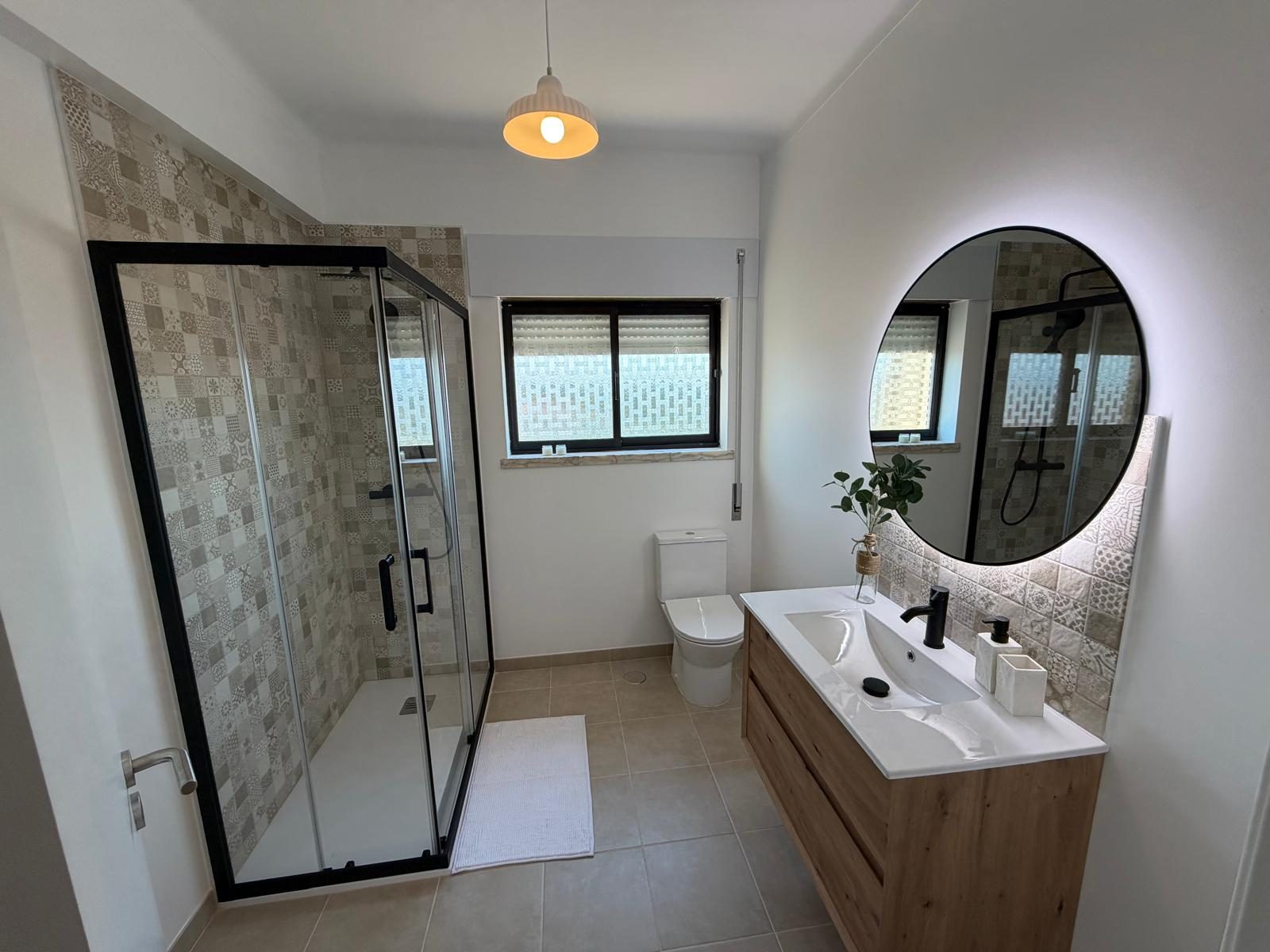 Casa de banho remodelada com base de duche, resguardo em vidro e móvel suspenso