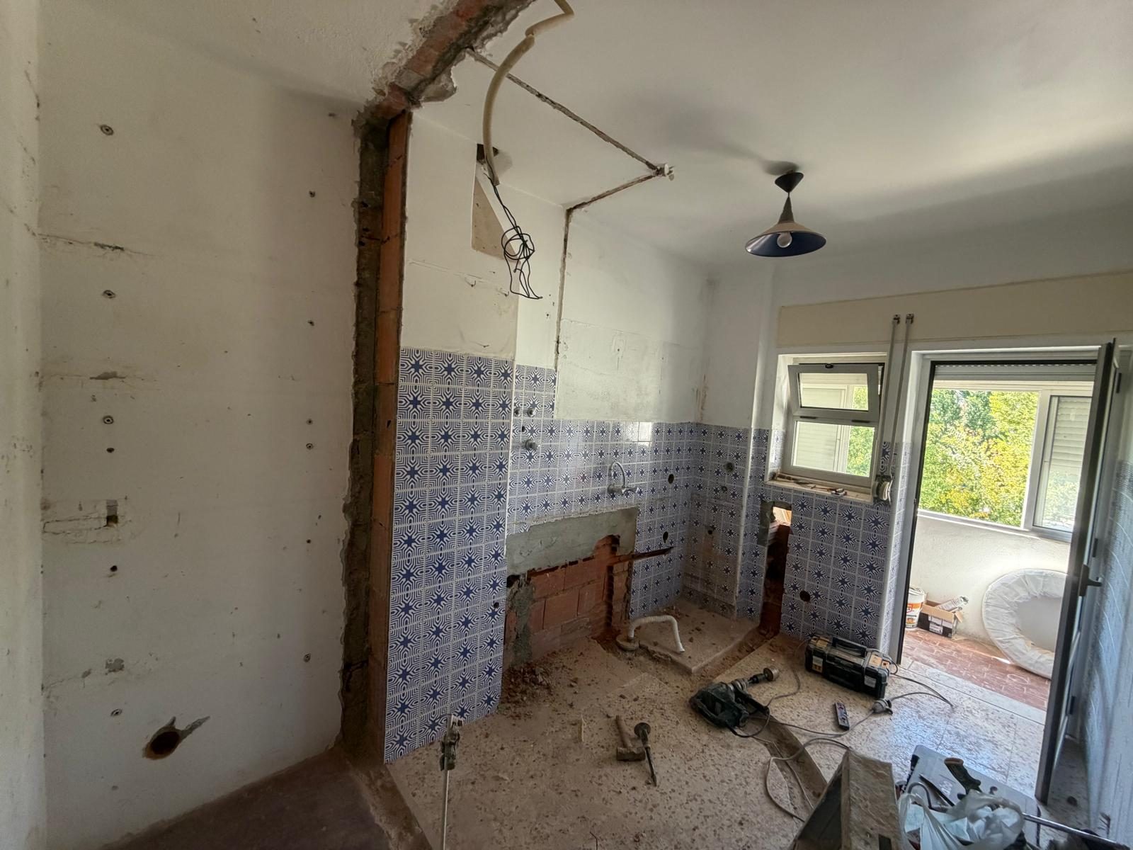 Cozinha antes da remodelação, com paredes picadas e azulejo antigo