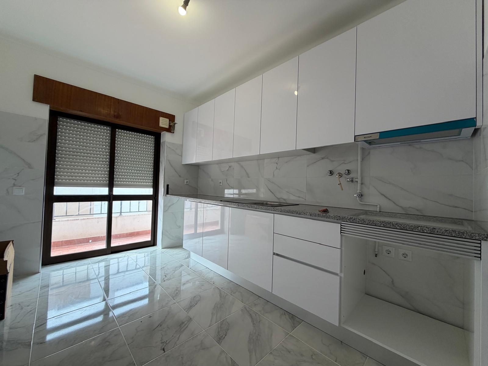 Cozinha nova com móveis brancos, bancada em granito e revestimento efeito mármore